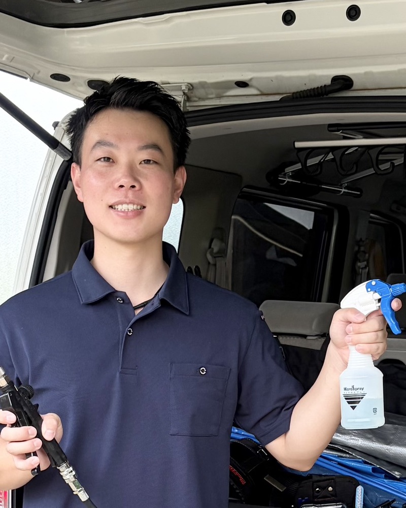 縁クリーンサービス代表 田中託也。作業車の前で洗浄用の道具を手にした笑顔の写真