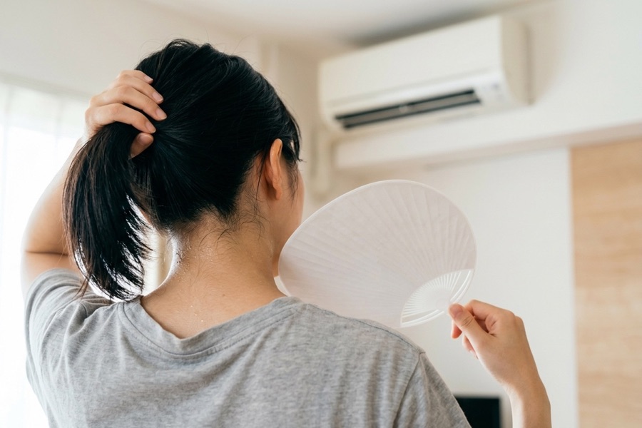 エアコンの効きが悪く、うちわであおぐ様子（イメージ）